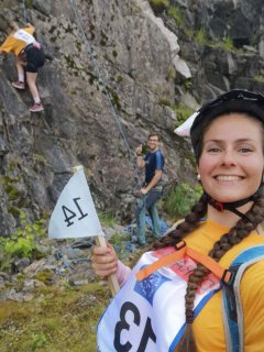 Anette Midtun poserar for kamera, makker Anja Grindheim på veg opp fjellknausen
